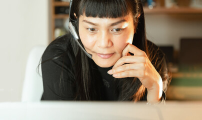Asian female person with headphones,microphone smile on call as contact center,telemarketing online networking.Happy woman consultant as virtual assistant at office in tech support,customer service