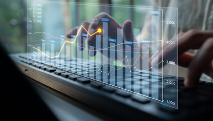 A close-up view of hands typing on a keyboard, with overlayed financial graphs and charts on the screen, illustrating data analytics and business growth in a modern office setting. Scalp