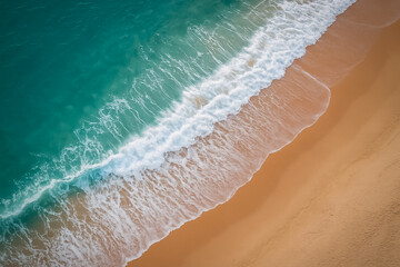 An aerial view of vibrant turquoise waves gently crashing onto a golden sandy beach. Ocean background for travel or nature themes with copy space.