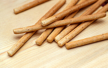 Close-up shot of scattered grissini sticks. Highlighting their healthy, crunchy texture and light nutritional snack value on a wooden table. Ideal for food packaging.
