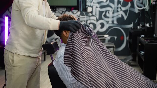 Barber placing a cutting cape on Arab customer in a modern barbershop