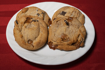 Cookies on white plate on red background (sea salt caramel chocolate chunk cookies)