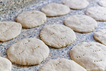 Unbaked dough rounds artfully arranged on a textured surface, offering a glimpse into culinary craft and preparation. 