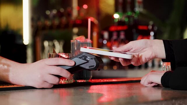 Bartender receiving contactless payment with smartphone at bar