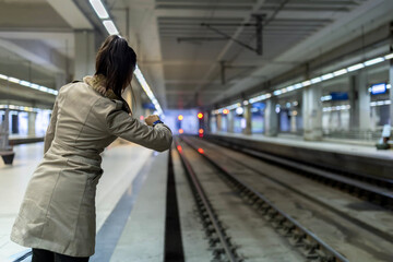 Woman checking smartwatch while waiting on subway platform