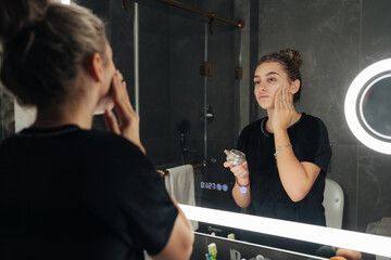 Influencer applying makeup in bathroom mirror with ring light