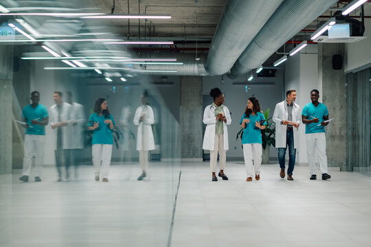 Diverse medical team walking hospital corridor collaborating