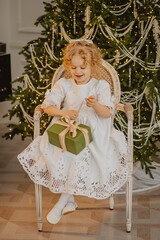 A charming 6-year-old blonde with curly hair in Christmas decorations 