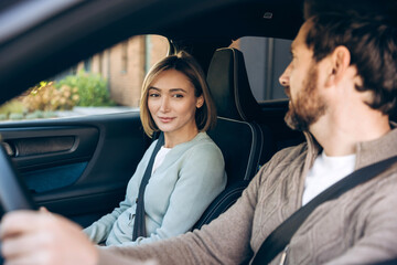 Smiling happy couple driving car talking enjoying road trip together
