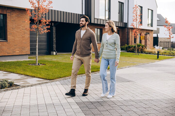 Happy couple walking hand in hand in modern suburb