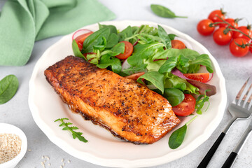 Grilled salmon fillet with fresh salad of cherry tomatoes, spinach and leafy greens. Healthy balanced meal. 