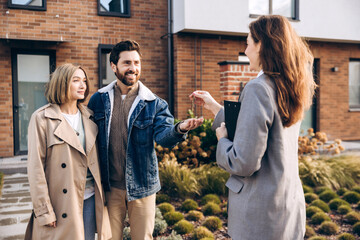 Happy couple receiving new house keys from real estate agent