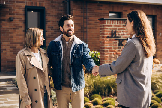 Happy smiling couple shaking hands with realtor after buying new home