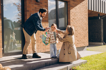 Parents helping child get ready for school outside house on the street
