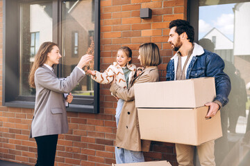 Confident, successful real estate agent handing keys to a happy family