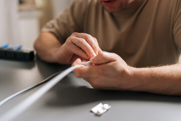 Cropped shot of male hands opening white inline electrical switch to repair or replace faulty...