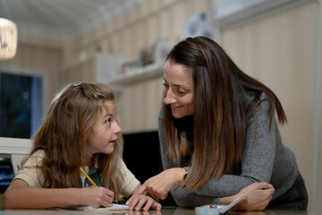 Mother helping young daughter learning homework
