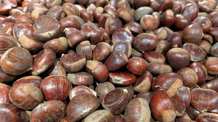 Fresh chestnuts scattered, showcasing their rich brown color and smooth texture, perfect for autumn recipes and seasonal culinary delights