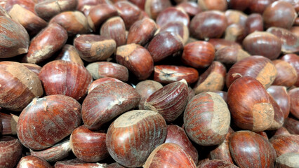 Fresh chestnuts scattered, showcasing their rich brown color and smooth texture, perfect for autumn recipes and seasonal culinary delights