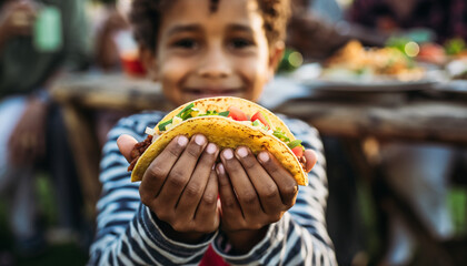 A happy, diverse child joyfully presents a vibrant, fresh taco brimming with delicious ingredients. Evokes healthy eating, cultural cuisine, and family togetherness at outdoor meals.
