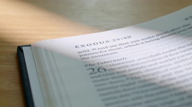 Close up macro footage showing Book of Exodus in paper Bible in English, with pages turning smoothly, revealing chapters, and sacred scripture for sermons or christian church.