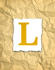 Gold letter "L" on torn paper, wrinkled texture