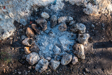 Top-down view of extinguished campfire ring with stones and ash in a forest area