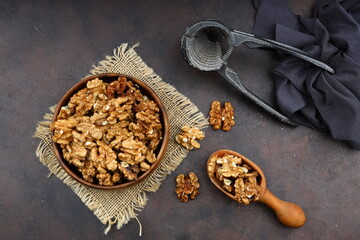Peeled walnuts in wooden bowl isolated on wooden background. Top view.