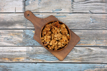 Peeled walnuts in wooden bowl isolated on wooden background. Top view.
