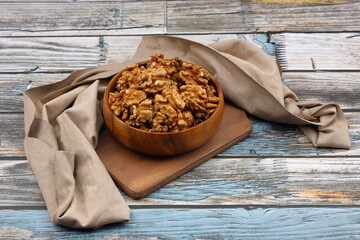 Peeled walnuts in wooden bowl isolated on wooden background. Top view.