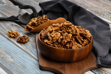 Peeled walnuts in wooden bowl isolated on wooden background. Top view.