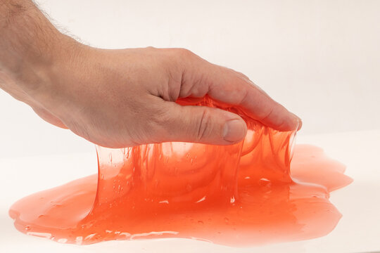 Red slime toy in man hand isolated on white.