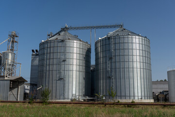 Tall silver silos store harvested grain under a clear blue sky.
