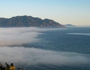 Misty coastal mountains meet a hazy sea