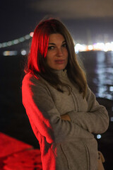 Obraz premium Young woman standing outside at night under red illumination