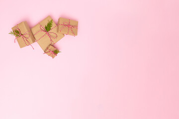 Craft gift boxes with twine and greenery on soft pink background with wide copy space for holiday sales, festive banners, greeting designs and seasonal marketing visuals.
