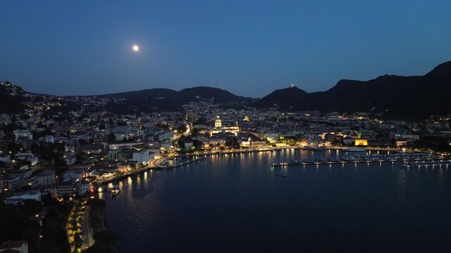 cinematic nocturnal aerial drone view of dazzling lights over Lake Como with motorboats leaving white trails on the blue waters 3