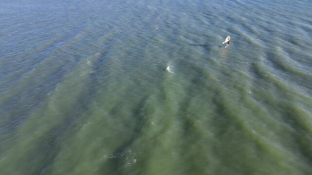 Cinematic aerial view of windsurfers performing acrobatics on a windy winter day along the blue Italian coast 3