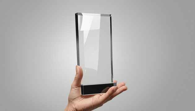 Hand holding transparent rectangle glass award, grey background, ai generated