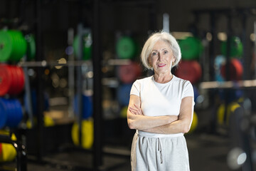 Senior woman trainer in sportswear poses in middle of fitness center gym. Active lifestyle,...