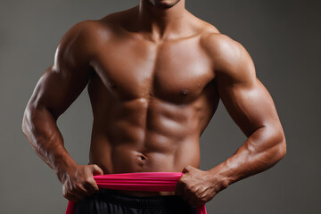 Muscular man demonstrating fitness and strength in studio with resistance band exercise