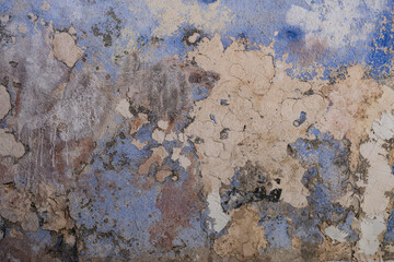Abstract weathered and cracked paint peeling on old blue and beige wall texture