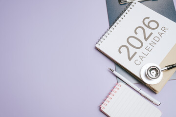 Business concept. 2026 calendar stethoscope pen notebook medical planning healthcare schedule workspace organization purple background office desk appointment reminder