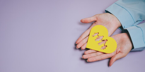 Family concept. Yellow heart paper cutout hands holding heart family symbol purple background caring gesture love concept human palm paper art protection relationship connection togetherness