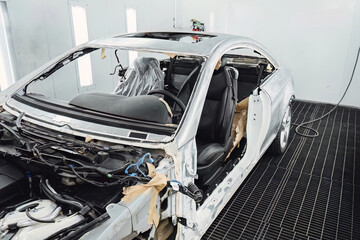 Car body shell completely disassembled after an accident in an auto service garage for major body repair and structural frame restoration work. Industrial shot for advertising and service promotion.