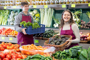 Portrait of female grocery store seller with basket of ripe kiwis in her hands