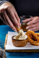 Hand dipping crispy calamari into creamy sauce