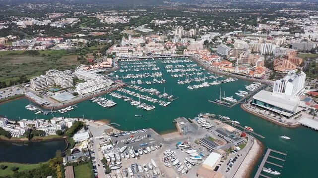 Vilamoura aerial view aerial view busy yacht basin with dense moored fleet, marina promenades, maintenance yards and coastal town buildings, energetic nautical hub and clear turquoise water