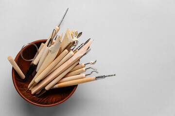 Bowl with set of sculptor tools on grey background