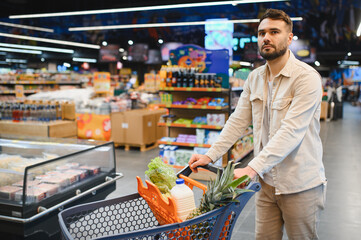 Man pushing shopping cart buying groceries in supermarket